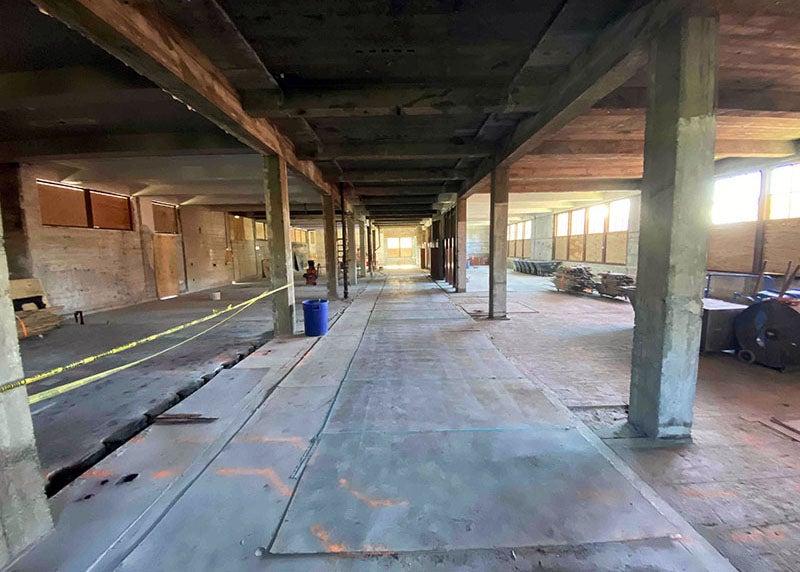 inside of a building partially torn up with posts and beams with some windows covered in wood and some open