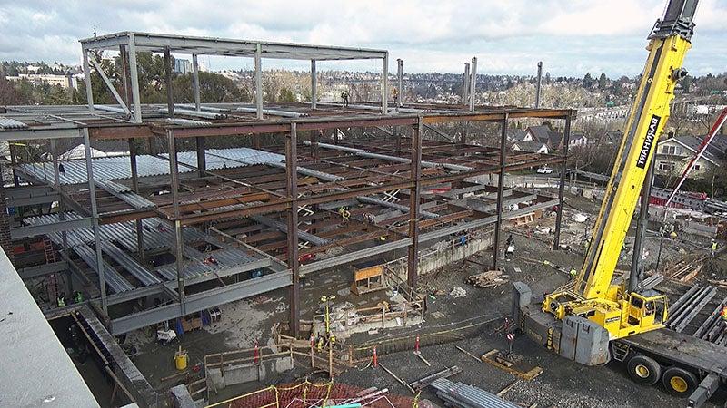 a steel framework for a 3 story building with a crane partially showing in the foreground