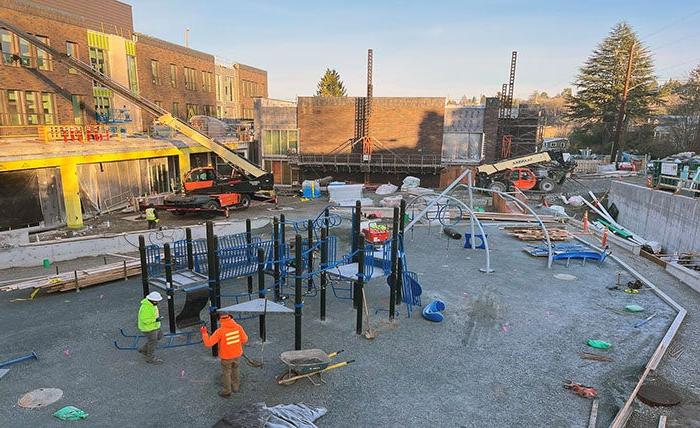 people are installing a play structure outside of a building under construction