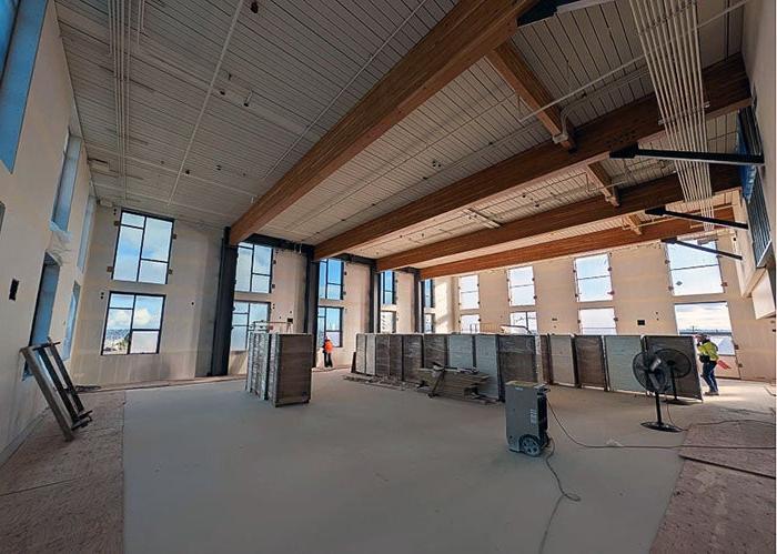 larger room partially completed with wood ceiling, large beams, and windows